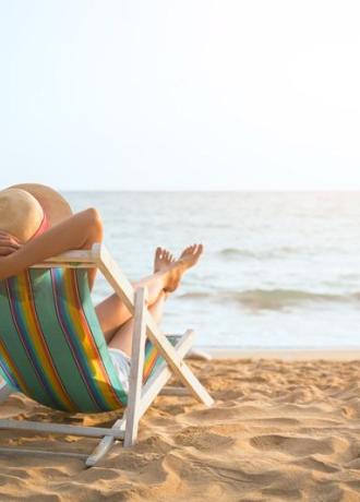 Persona rilassata su una sedia a sdraio in spiaggia al tramonto.