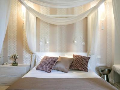 Camera da letto con baldacchino, cuscini decorativi e luci soffuse.