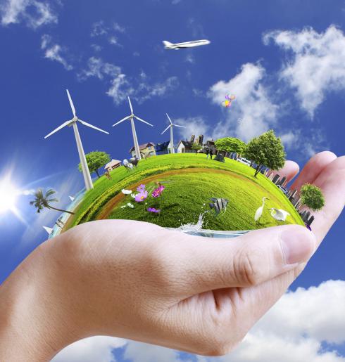 Mano che sostiene un mondo verde, energia e natura in armonia.