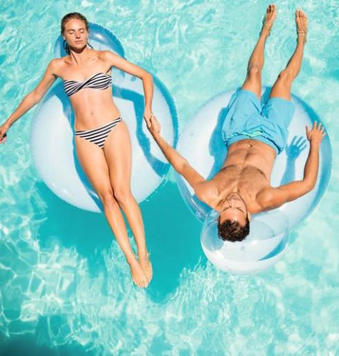 Due persone rilassate galleggiano su ciambelle in una piscina luminosa.