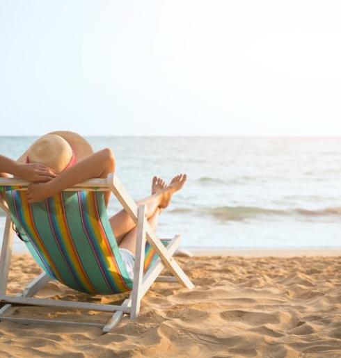 Persona rilassata su una sedia a sdraio in spiaggia al tramonto.