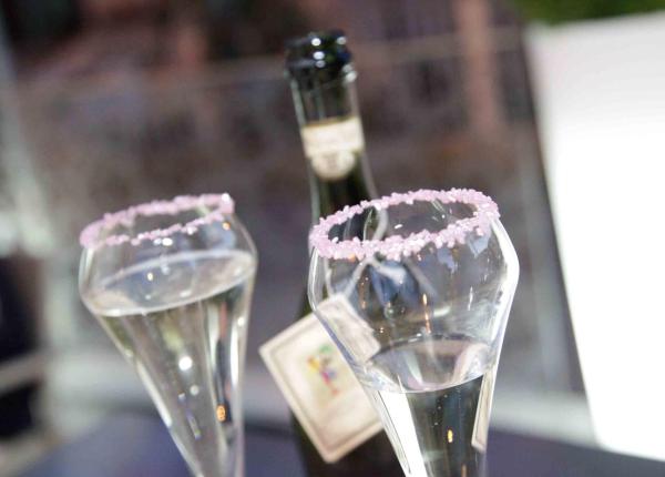 Calici di champagne con bordo zuccherato rosa, atmosfera romantica.