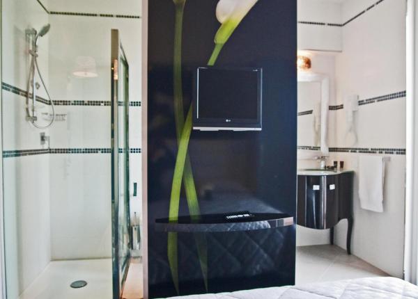Camera elegante con doccia, televisore e fiori stilizzati.