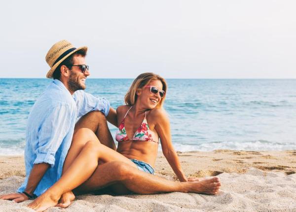 Couple heureux sur la plage, soleil, mer et sourires.