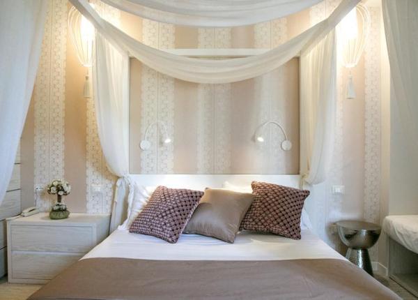 Camera da letto con baldacchino, cuscini decorativi e luci soffuse.